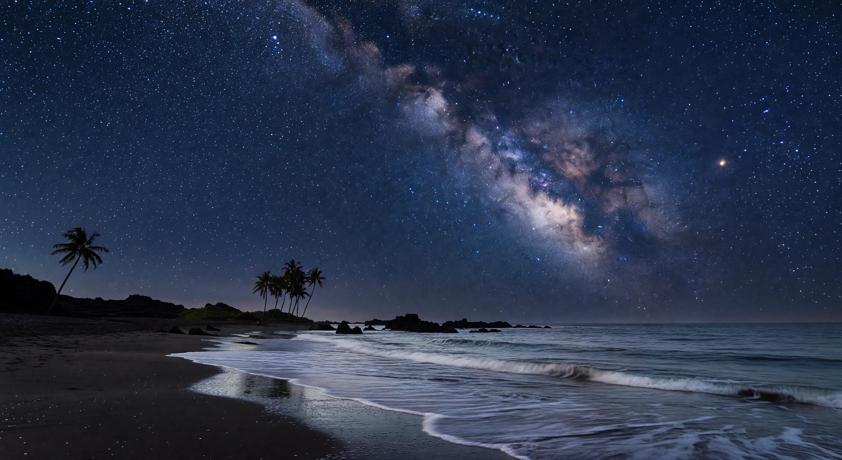 Starry night over Okinawa beach with bioluminescent sea